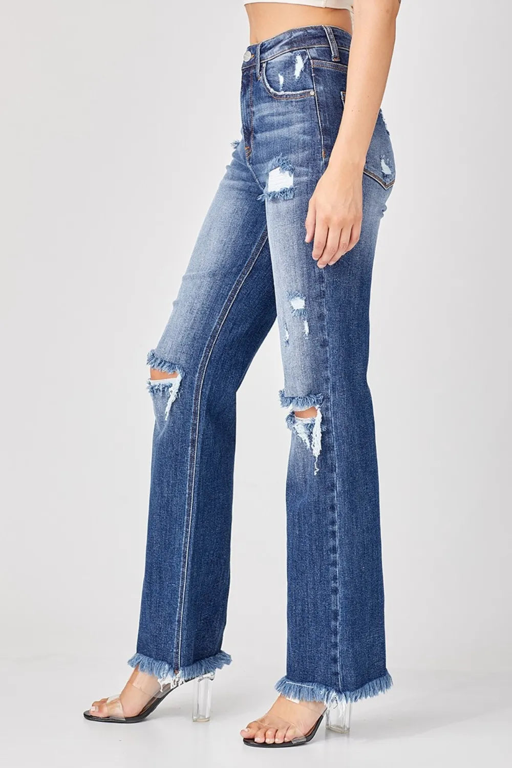 Distressed blue jeans worn by a person on a white background