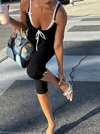 Woman in black outfit with white accents crossing a street, holding a blue handbag.