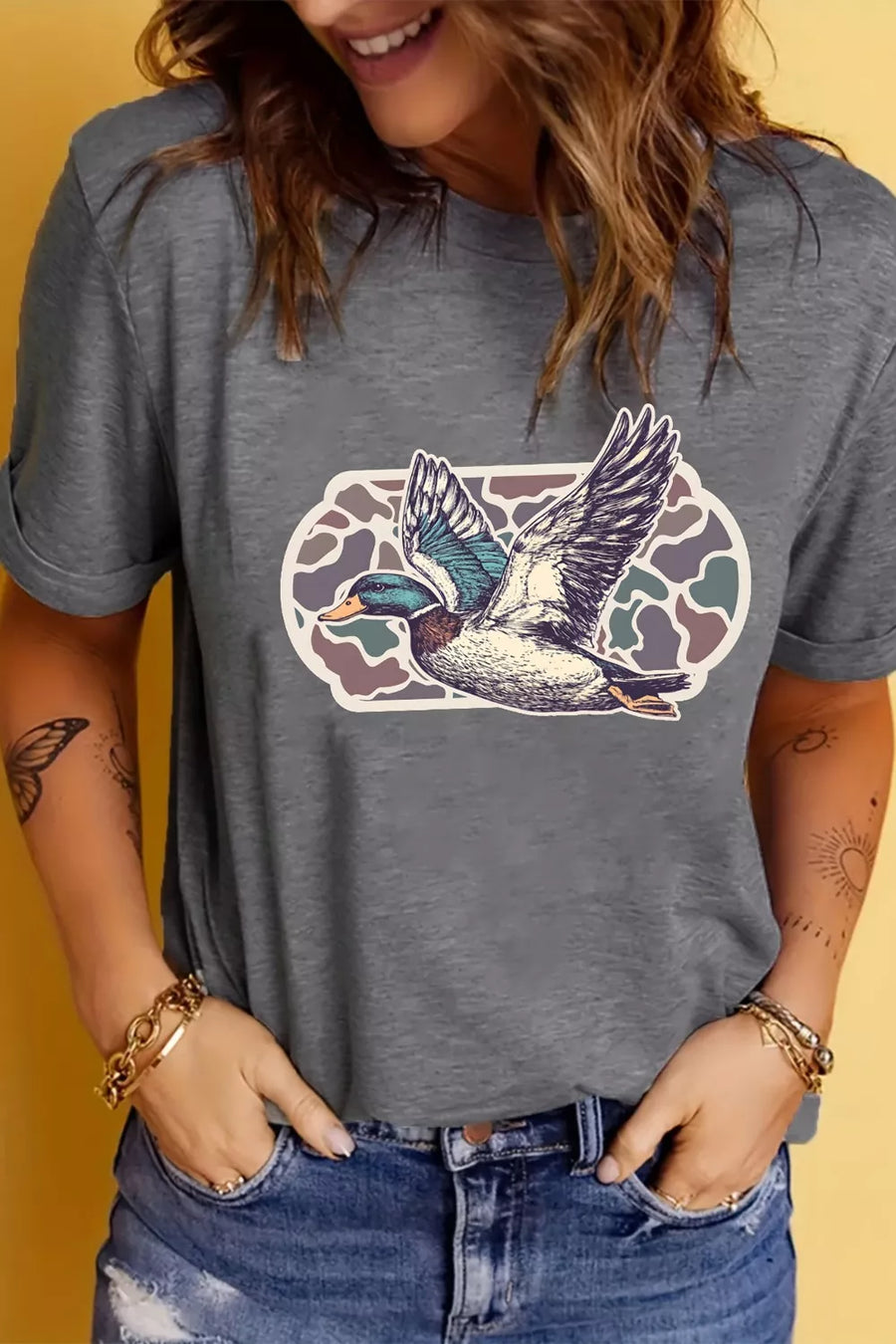 Person wearing a gray t-shirt with a duck graphic on a yellow background