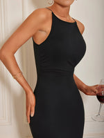 Woman in a black dress holding a glass of red wine against a neutral background