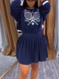 Person wearing a navy blue outfit with a tennis-themed design in front of a brown curtain.
