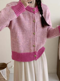 Pink knitted cardigan worn by a person with a white background