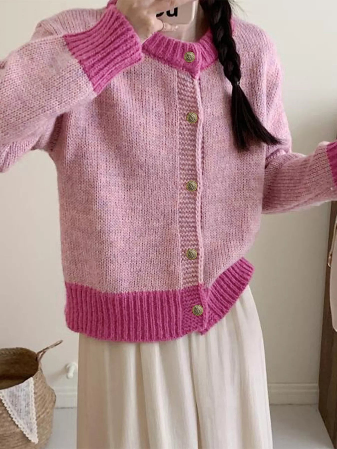 Pink knitted cardigan worn by a person with a white background