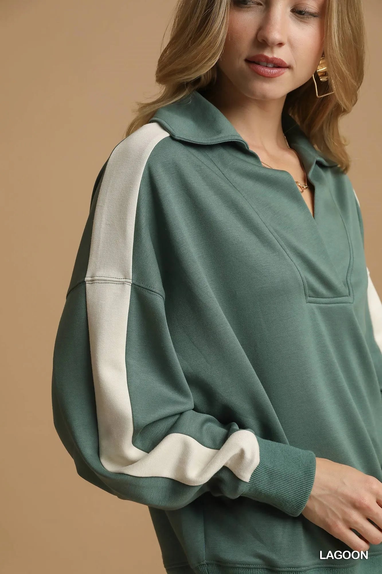 Green and white long-sleeve top worn by a person on a beige background
