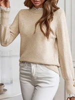 Woman wearing a beige sweater with lace trim sleeves and collar, standing against a white background.