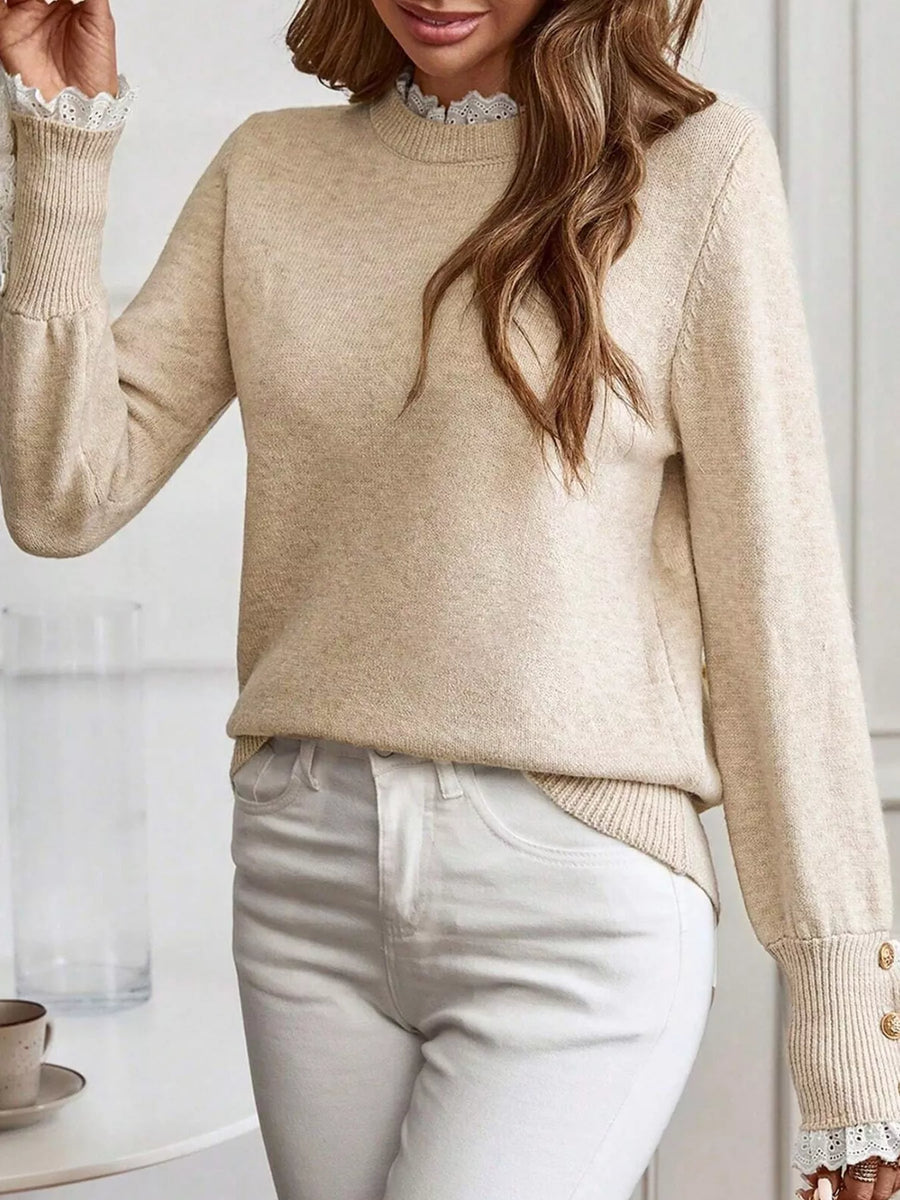 Woman wearing a beige sweater with lace trim sleeves and collar, standing against a white background.