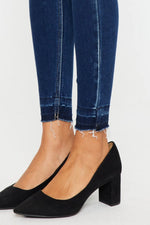 Black high-heeled shoes worn with blue jeans on a white background