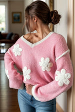 Woman wearing a pink sweater with white flower patterns indoors.