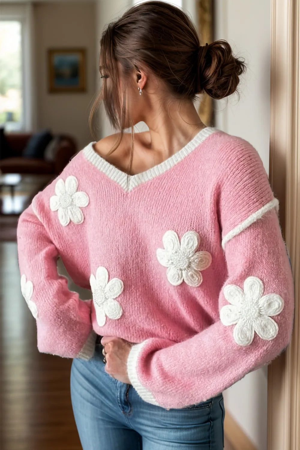Woman wearing a pink sweater with white flower patterns indoors.