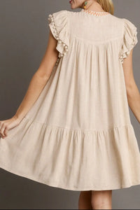 Beige dress with ruffled sleeves on a plain background