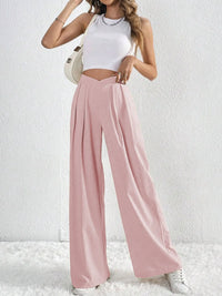 Woman wearing a white top and pink wide-leg pants against a white background