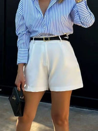 Person wearing a blue and white striped shirt with white shorts against a black background
