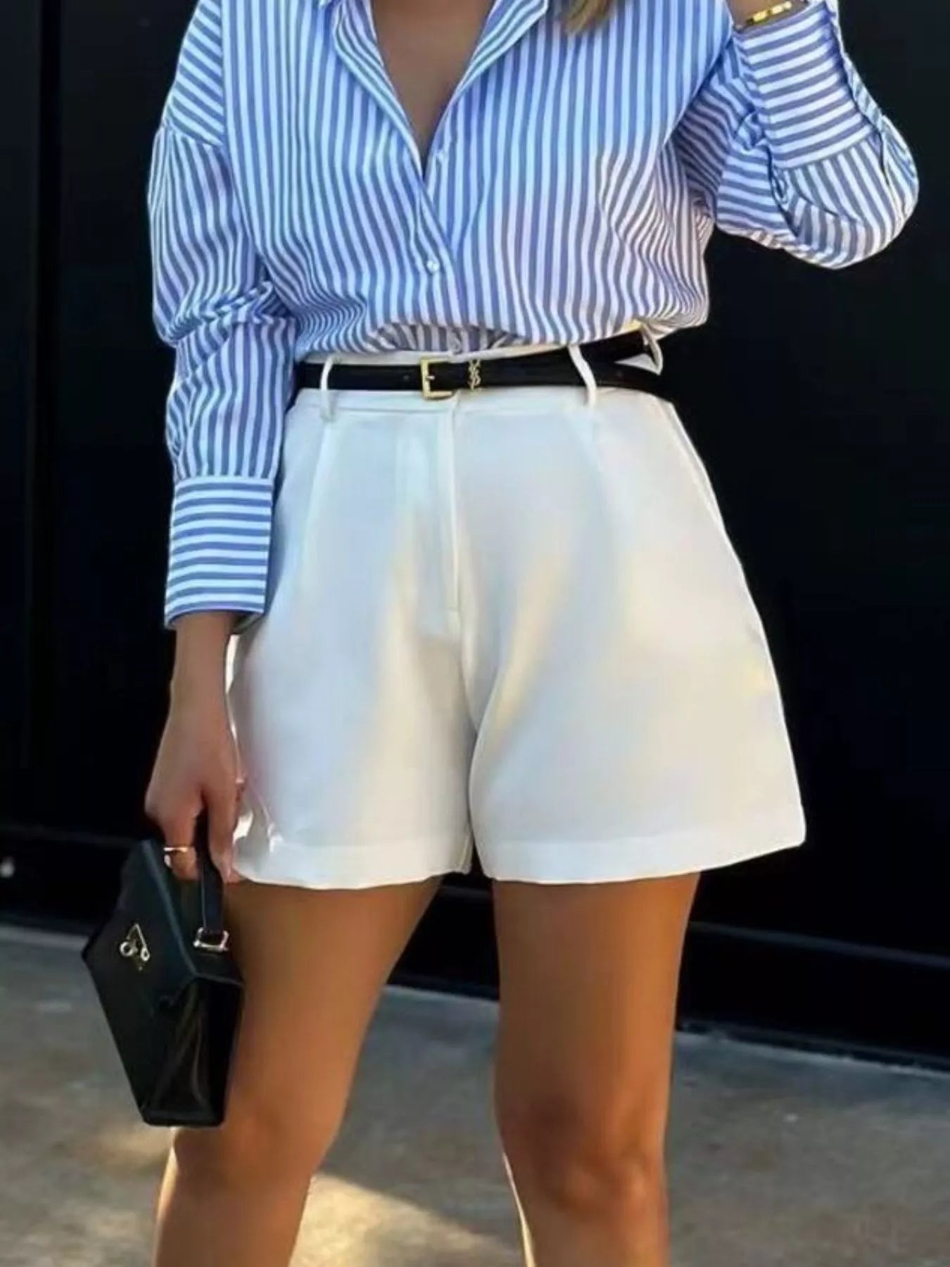 Person wearing a blue and white striped shirt with white shorts against a black background