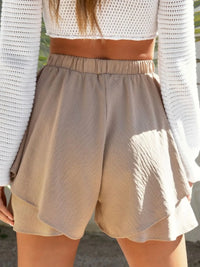 Beige shorts worn by a person with a blurred background