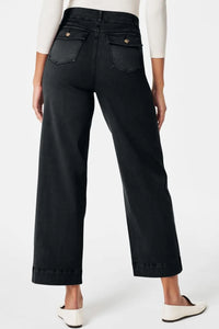 Person wearing black wide-leg jeans on a white background