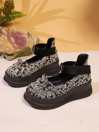 Black and white floral patterned shoes on a light background