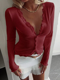 Person wearing a red long-sleeve top with lace details and a white skirt.