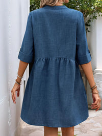 Blue dress worn by a person standing against a white wall.