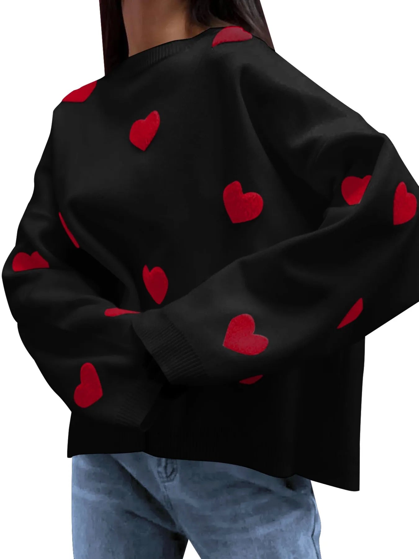 Black sweater with red heart patterns worn by a person on a white background