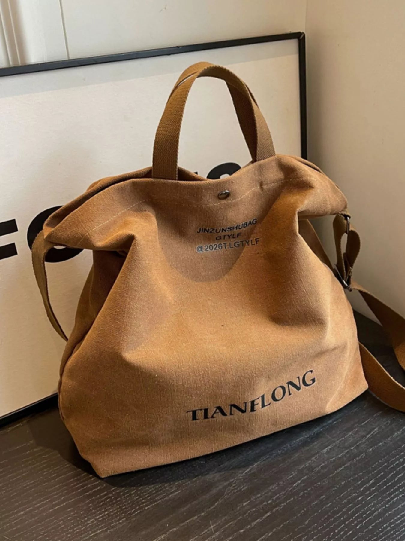 Brown leather bag with 'TIANFONG' branding on a wooden surface.