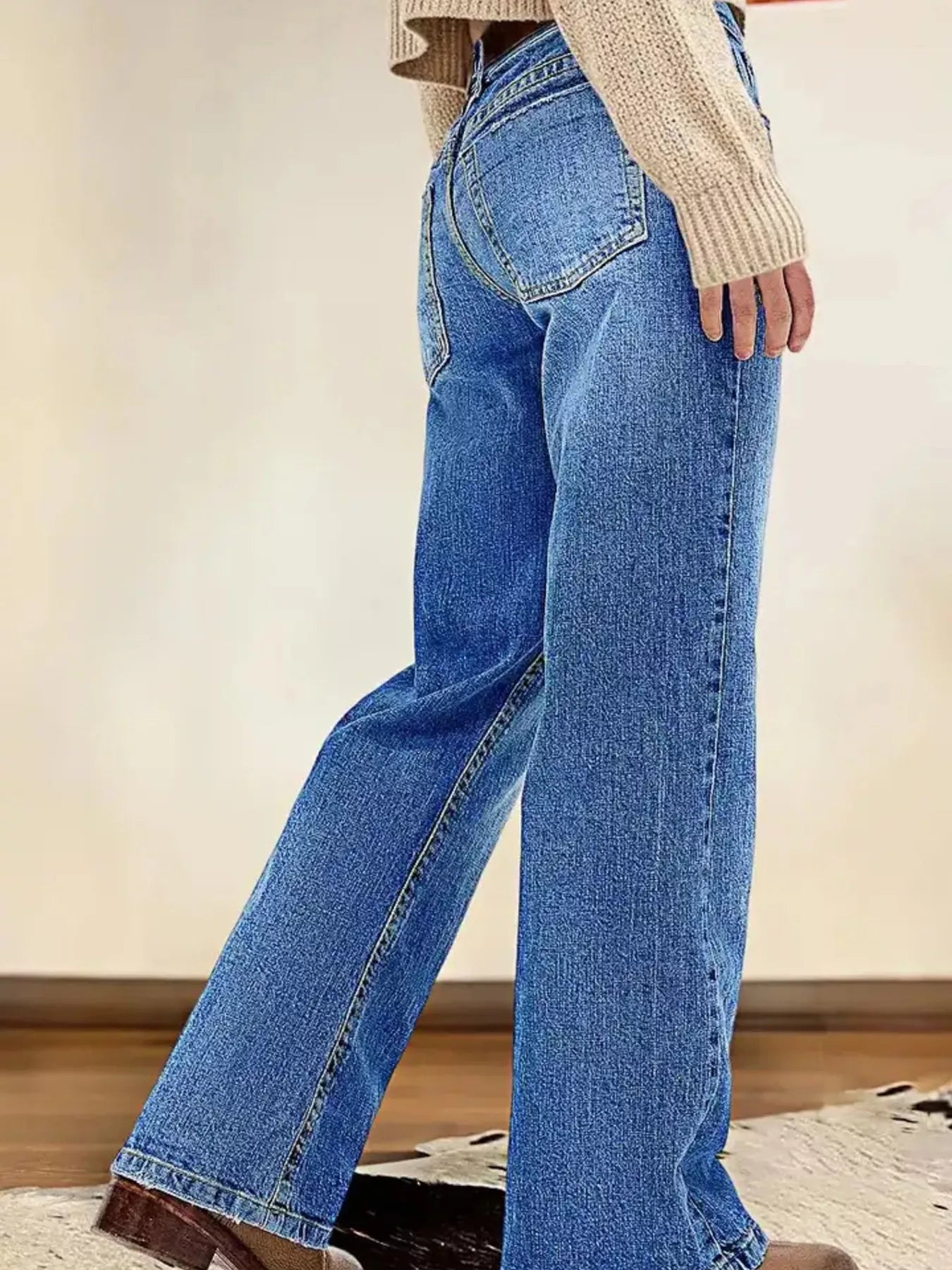 Person wearing blue jeans with a neutral background