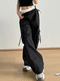 Person wearing black cargo pants on a wooden floor with a white wall background