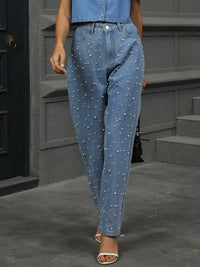 Person wearing blue jeans with pearl embellishments in an urban setting.