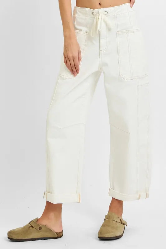 Person wearing white pants with a drawstring waist on a plain background
