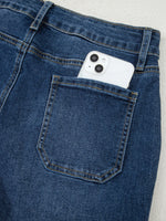 White phone in a blue jeans pocket on a light gray background