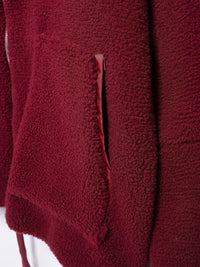Close-up of a textured burgundy fabric with a zipper.