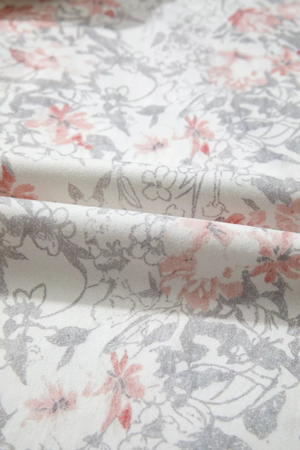 Floral patterned fabric with pink and gray flowers on a white background