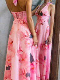 Woman wearing a pink floral dress standing in front of a mirror.