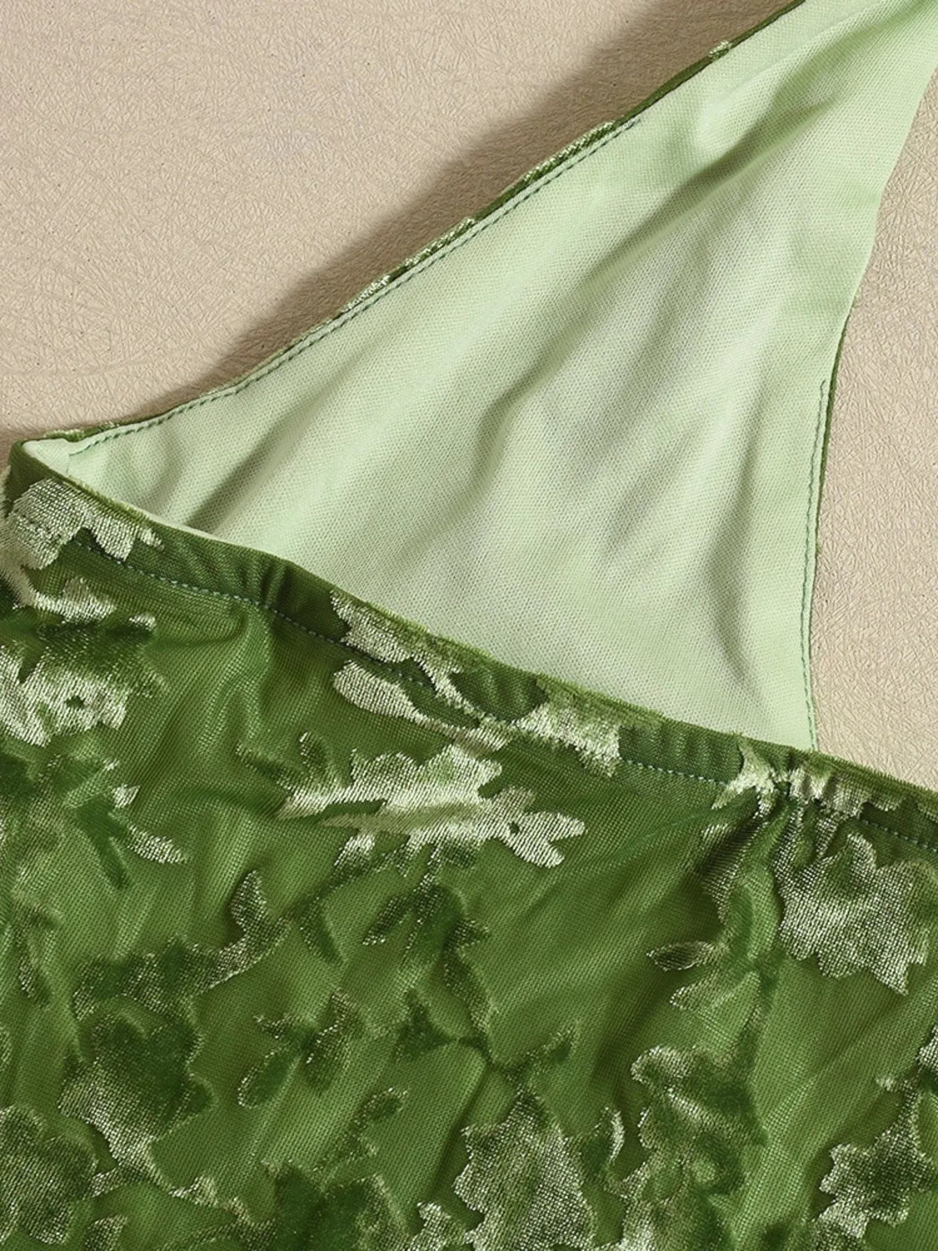 Green lace fabric with a textured pattern on a beige background