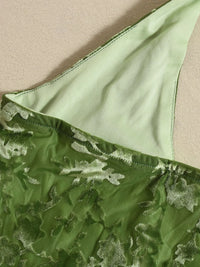 Green lace fabric with a textured pattern on a beige background