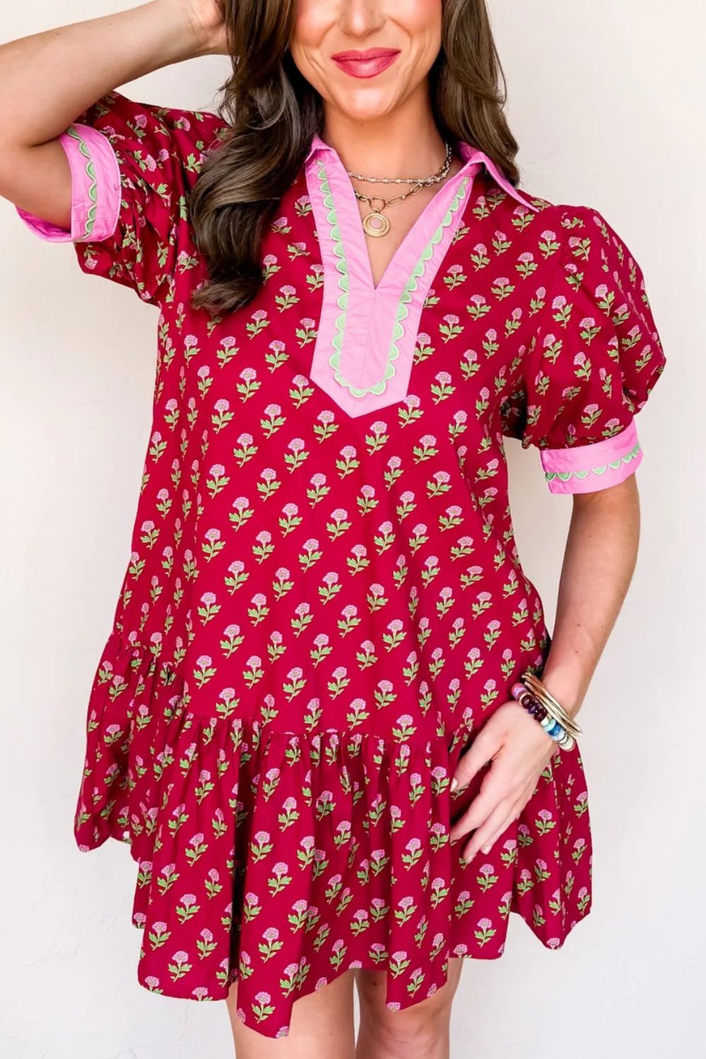 Woman wearing a red floral dress with pink trim against a white background