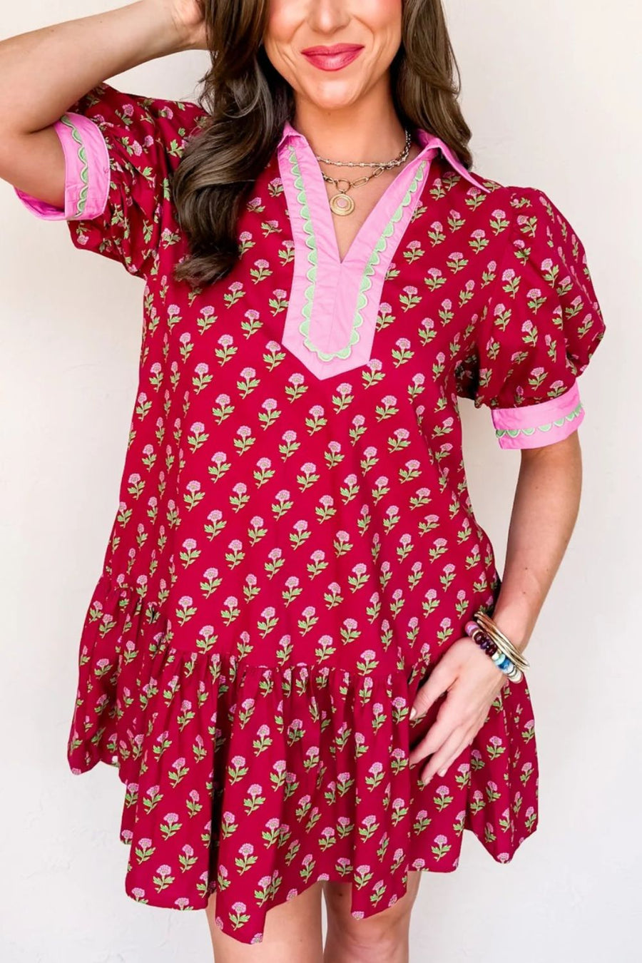 Woman wearing a red floral dress with pink trim against a white background