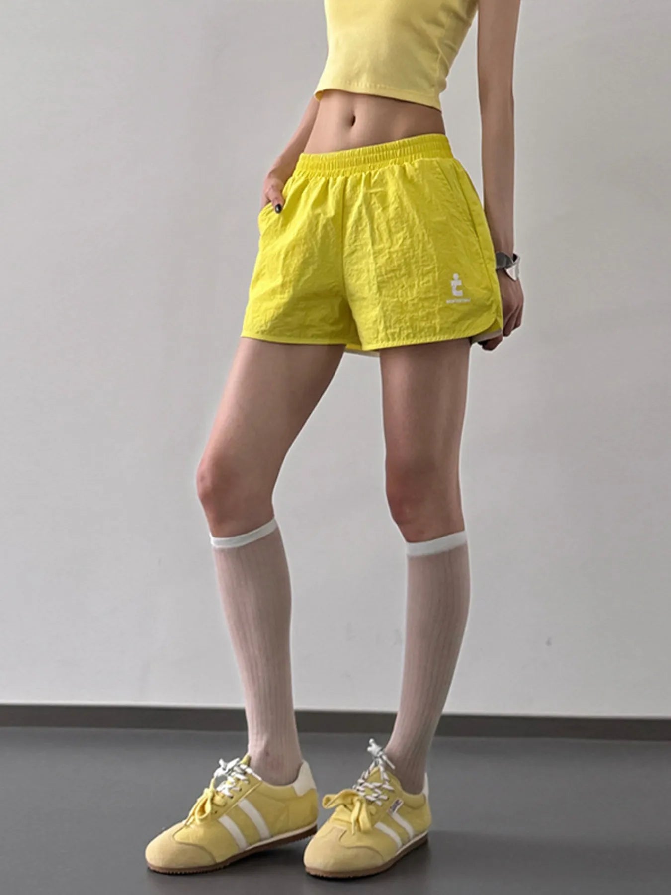 Person wearing yellow shorts and shoes on a plain background