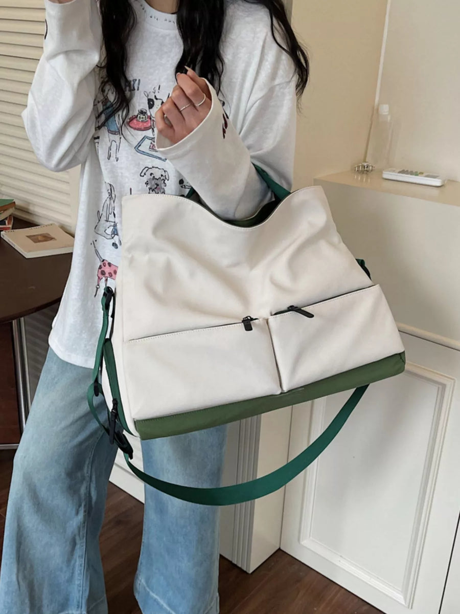 Person holding a white tote bag with green straps in an indoor setting