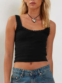 Woman wearing a black tank top and blue jeans against a plain background