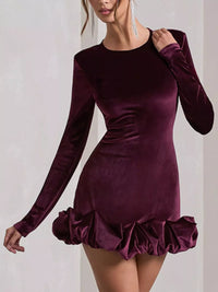 Purple velvet dress with long sleeves and ruffled hem on a plain background