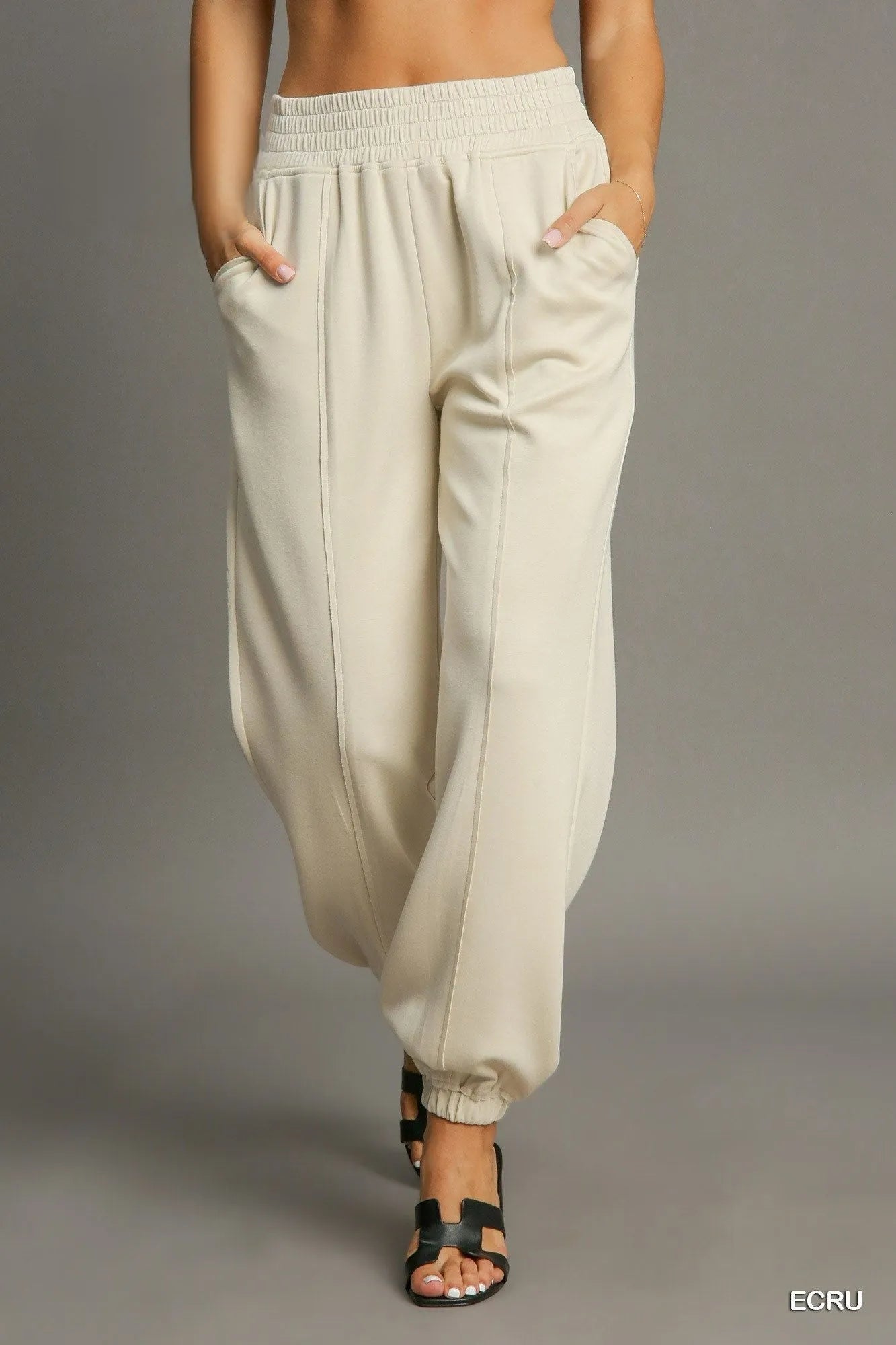 Beige wide-leg pants worn by a person on a gray background