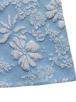 Close-up of blue fabric with white floral lace embroidery