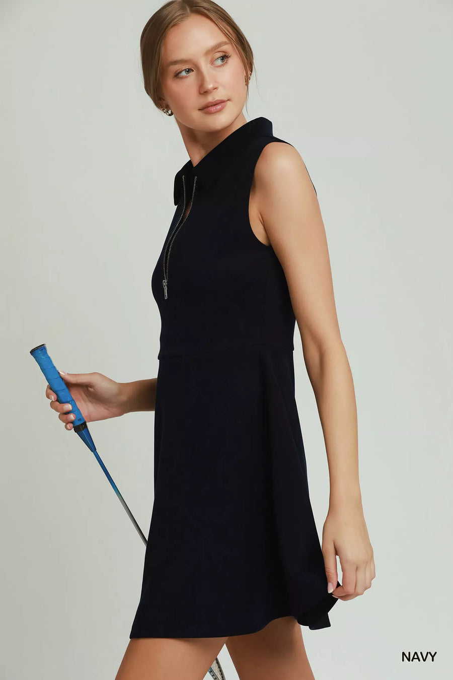 Woman wearing a black sleeveless dress holding a blue object on a light gray background