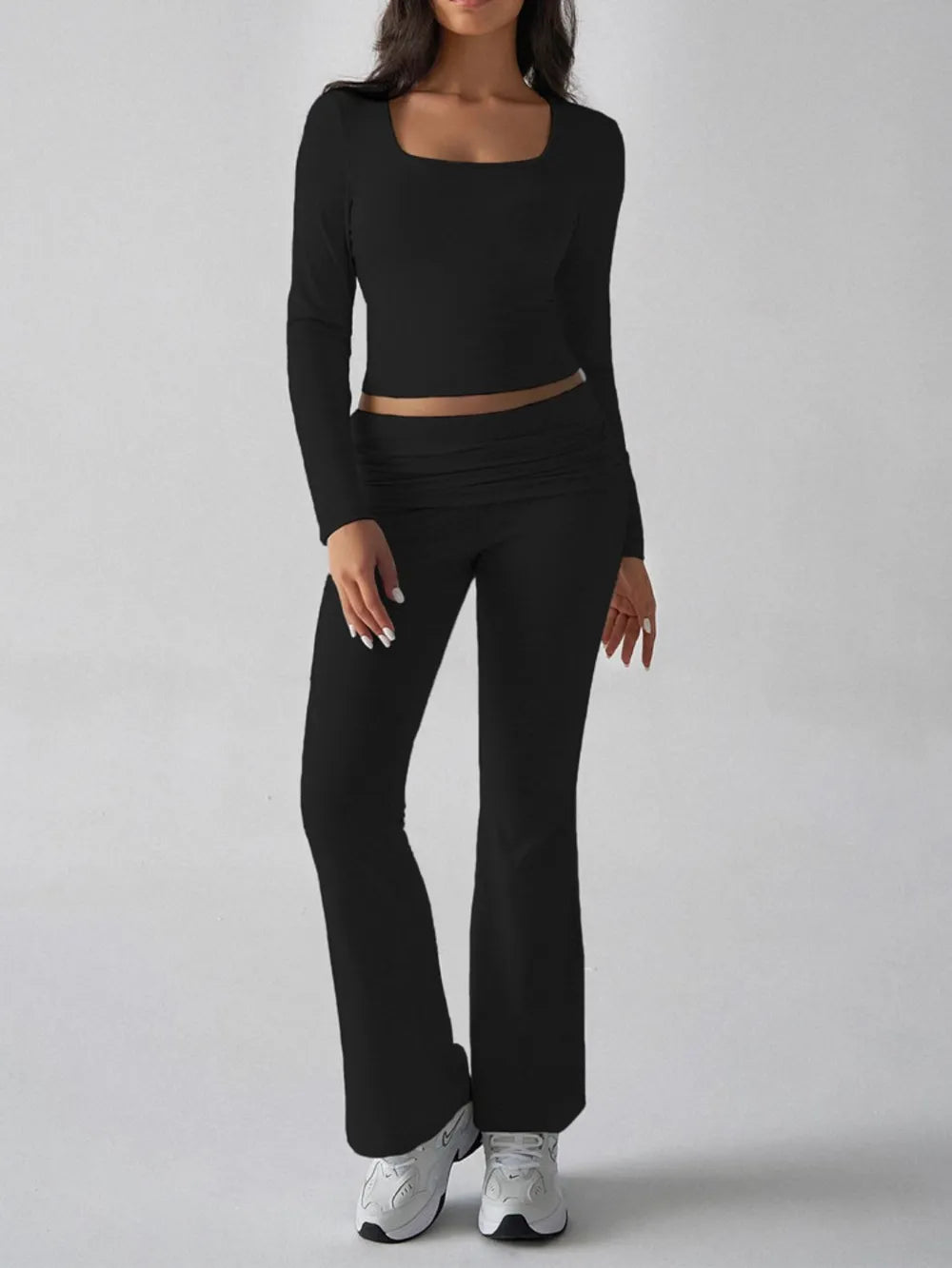 Person wearing a black long-sleeve top and black pants on a white background