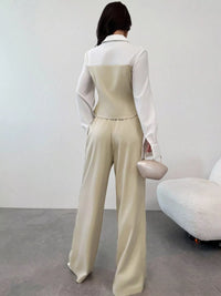 Person wearing a beige jumpsuit with a white shirt underneath, standing against a plain background.