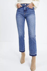 Blue jeans worn with beige ankle boots on a white background