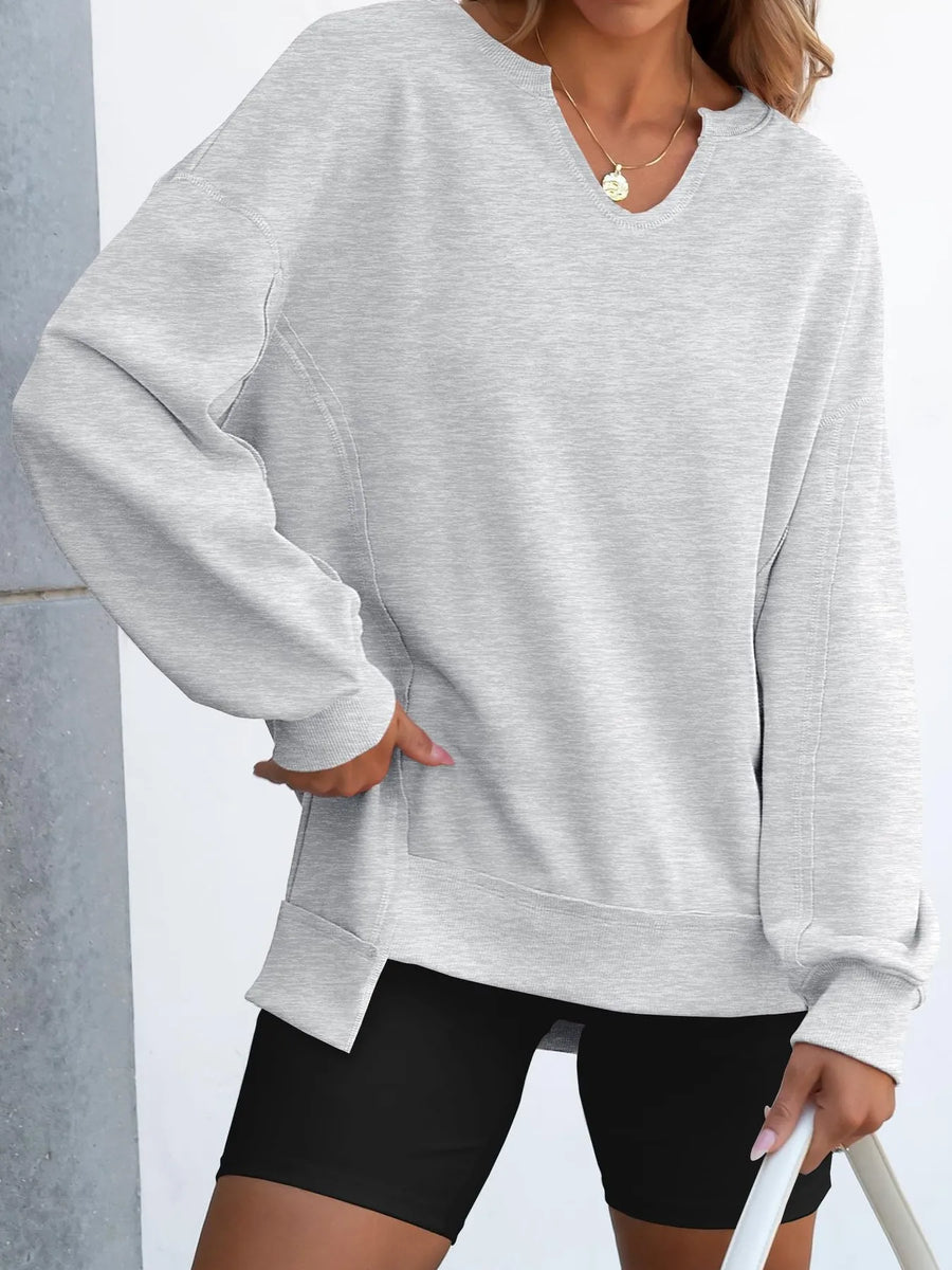 Person wearing a gray sweatshirt and black shorts against a light background