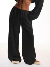 Black wide-leg pants worn by a person on a white background