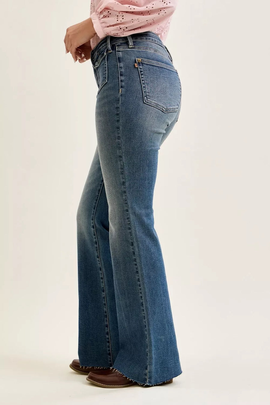 Person wearing blue flared jeans on a plain background