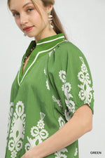 Woman wearing a green dress with white floral patterns on a plain background